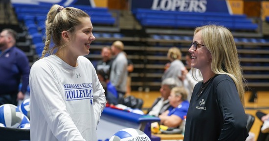 UNK setter Peyton Neff, left, and assistant coach Maddie Squiers chat before a recent match at the Health and Sports Center. Neff has been learning from Squiers since they were teammates in 2021. (Photo by Erika Pritchard, UNK Communications)